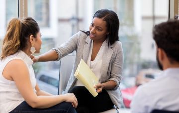 woman places hand on other woman in therapy session